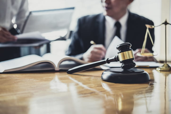 A dog bite attorney is working on paperwork at his desk. In front of him is the scales of justice and a gavel.