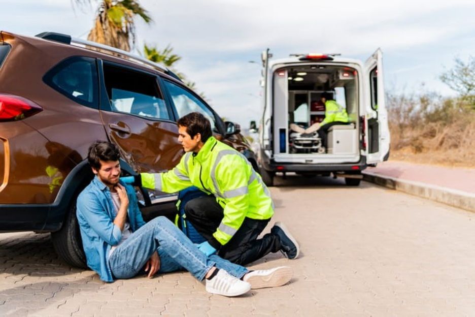 A paramedic assists an injured man after car accident since he is in shock.